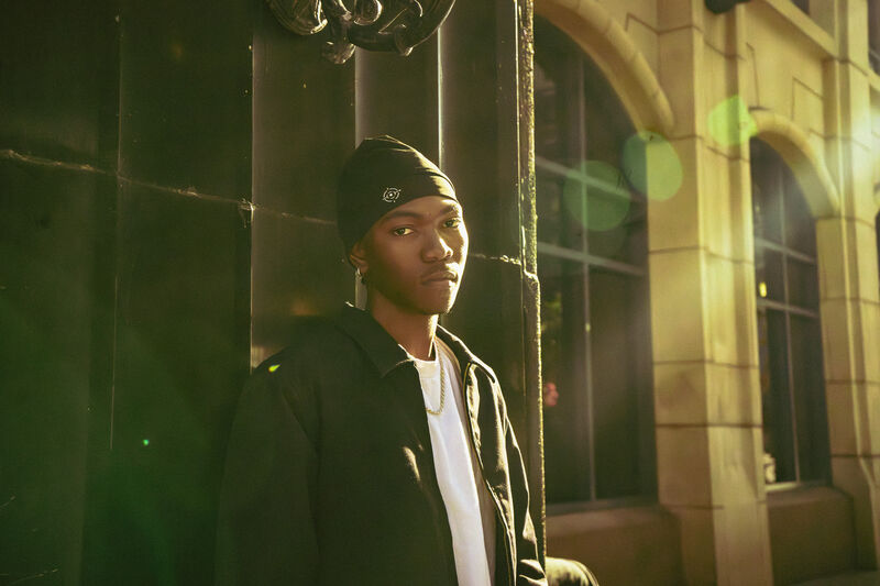 Model in a streetwear beanie at a downtown intersection