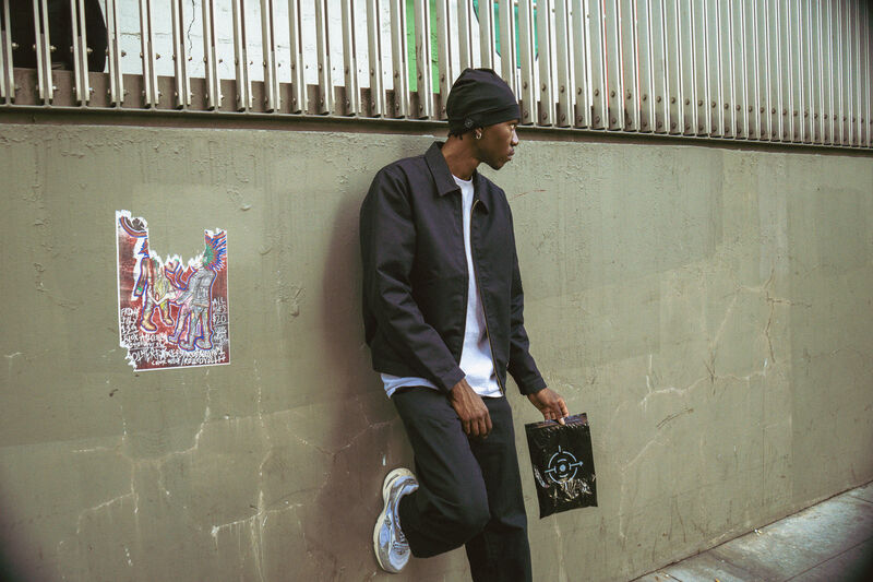 Model in a black and green hoodie against a chalkboard